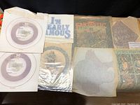 Top-down view of all 8 vintage iron-on patches laid out on a surface, showing band names and slogans.