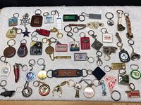 Full view of entire lot of key chains spread on white surface showing various designs and materials