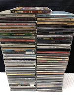 Stacks of CD jewel cases showing spines with artist and album titles arranged in three columns