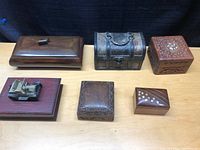 Overview photo showing all six wooden boxes in the lot arranged in two rows on a wooden table with black backdrop.