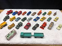 Photo showing all 29 vintage die-cast toy vehicles arranged in rows on a white background.