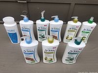 Front view of all nine bottles of body lotions mostly from St. Ives and one Ivory bottle, arranged on the floor.