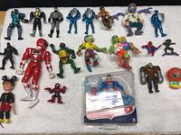 Full lot of figure toys arranged on white fabric surface showing various characters and sizes