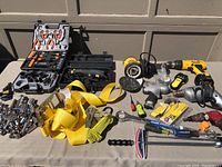 Overview of multiple power tools, ratchets, screwdrivers, socket set, and yellow ratchet straps on a table