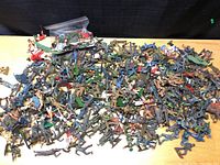 Wide top-down view showing a large mix of vintage plastic soldiers in multiple colors and styles including infantry and cavalry figures.