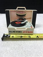 Miniature Rolling Stones Let It Bleed record player next to tape measure showing about 3 inches wide.