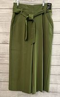 Front view of olive green crop pants showing fabric belt tied at front and side pockets.