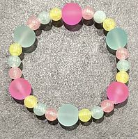 Top view of the pastel chunky beaded wrist bracelet showing alternating frosted beads in light pink, yellow, aqua green, and blue, arranged in a circular elastic band.