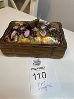 Rectangular wooden box with colorful abstract art on the lid and small wooden handle. Box edges have a carved woven pattern.