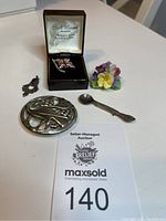 Overall view of all items including pins and pendant on the table with auction tag 140.