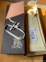 Closed box with ivory tablecloth and tag visible