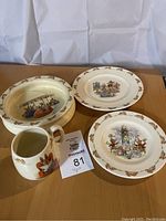 Four pieces of Bunnykins dinnerware including bowl, two decorated plates, and pitcher with Bunnykins themed illustrations and a chip repaired on the bowl