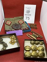 Assortment of Canadian military buttons, pins, cloth patches, and insignia arranged on red fabric background with auction lot card