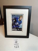 Full view of framed signed photo of Darryl Sittler in black frame on a white surface.