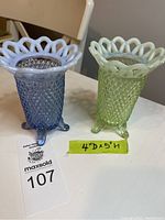 Photo of two Fenton glass vases, one green uranium glass that glows in the dark, and one blue opalescent glass, both with lattice ruffled rims and hobnail diamond texture, each with three small feet.
