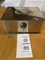 Top and front view showing the shiny chrome lockbox with metal handle and key in lock cylinder