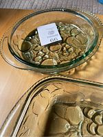 Round pie dish and rectangular dish showing embossed orchard fruit pattern in thick green glass