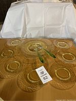 Overall photo showing the uranium green glass platter, seven lunch plates, and two salad servers arranged on a table.