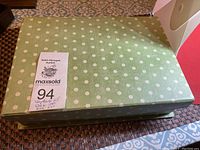 Closed green box with white polka dots holding assorted vintage jewelry