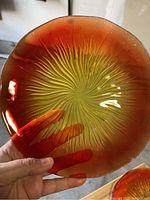 Close-up of an Amberina glass plate showing the sunburst pattern and gradient coloring from yellow to amber-red.