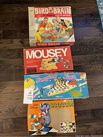 Four vintage board games including Bird Brain, Mousey, Jumping Jack, Disney Scacchi shown in closed boxes on floor.