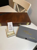 Photo of wooden rummy box, dominoes box, mini domino tiles and small box of miniature dice on table