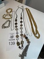 Top view of various vintage jewelry including necklaces and bracelets laid flat on a white surface.