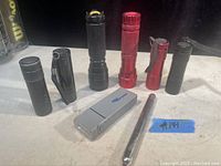 Photo of 8 flashlights arranged in two rows on a surface, showing different colors and styles.