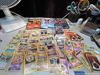 Photo of laid out Pokemon cards including standard cards and oversized cards, plus a sealed box.