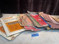 Stack of assorted sandpaper sheets fanned out on a surface.