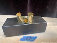 Photo of the vintage Rafael Canada cuff bracelet with amber-colored stone on top of a box.