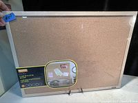 Front view of new Quartet cork bulletin board with protective plastic and label showing size and brand.