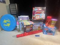 Photo showing the entire kids lot including the box of chalk, craft kits, big bubble maker wand, Play-Doh container, bubble solution pack, and blue flying disc with dolphin design.