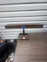 Front view of the mid-century modern desk lamp showing woodgrain finish on shade and base with adjustable neck and switch on the base.