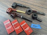 Four tobacco pipes and three Amphora absorbent filter boxes placed on a wooden surface.
