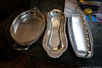 Three silverplate serving dishes arranged side by side on a countertop showing shape and size differences.