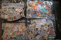 Four large bags filled with used Canadian postage stamps, showing assorted designs and colors.