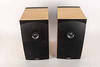 Pair of ENERGY eXL bookshelf speakers shown from the front with maple wood top and sides and black front faceplates with fabric grilles removed