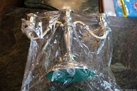 Photo shows Oneida silverplate candelabra partially wrapped in plastic, highlighting the shiny finish and three candle holders arranged with classic curved arms.