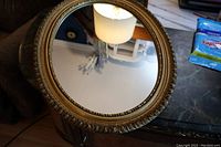 Close-up photo of the oval mirror showing detailed wood plaster frame with beaded inner edge.