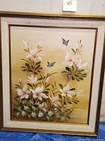 Full view of the framed 20th century signed oil on canvas painting showing white flowers and two blue butterflies against a light background.