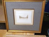 Framed engraving showing entire artwork and frame with gray fabric inner mat and gold frame