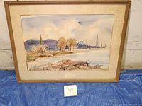 Full view of the framed watercolor painting showing the landscape lake scene with foliage and hills.
