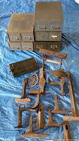 Top-down photo showing shoe forms, cobbler's tools and three stacked weathered metal card catalog drawers on a blue tarp.
