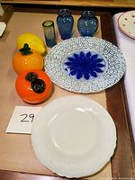 Photo of all items including Vaseline glass fruits, glass vases, fused glass dish with blue floral design, and white plate.