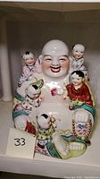 Front angle of ceramic Laughing Buddha with five children figures, showing detailed facial expressions and colorful robes.