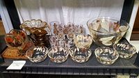 Full view showing entire collection with various glass bowls, pitcher, drinking glasses, vase, and amber and clear lucite items on display