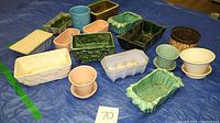 Overview of 14 assorted ceramic plant pots on blue tarp, various shapes, colors, and styles visible