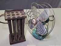 Photo showing both the Eskimo table fan and the vintage candle mold side by side on a white surface with a purple background.