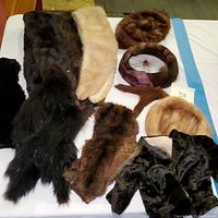 Full view of vintage mink hats, collars, and doll-sized coat arranged on a table.